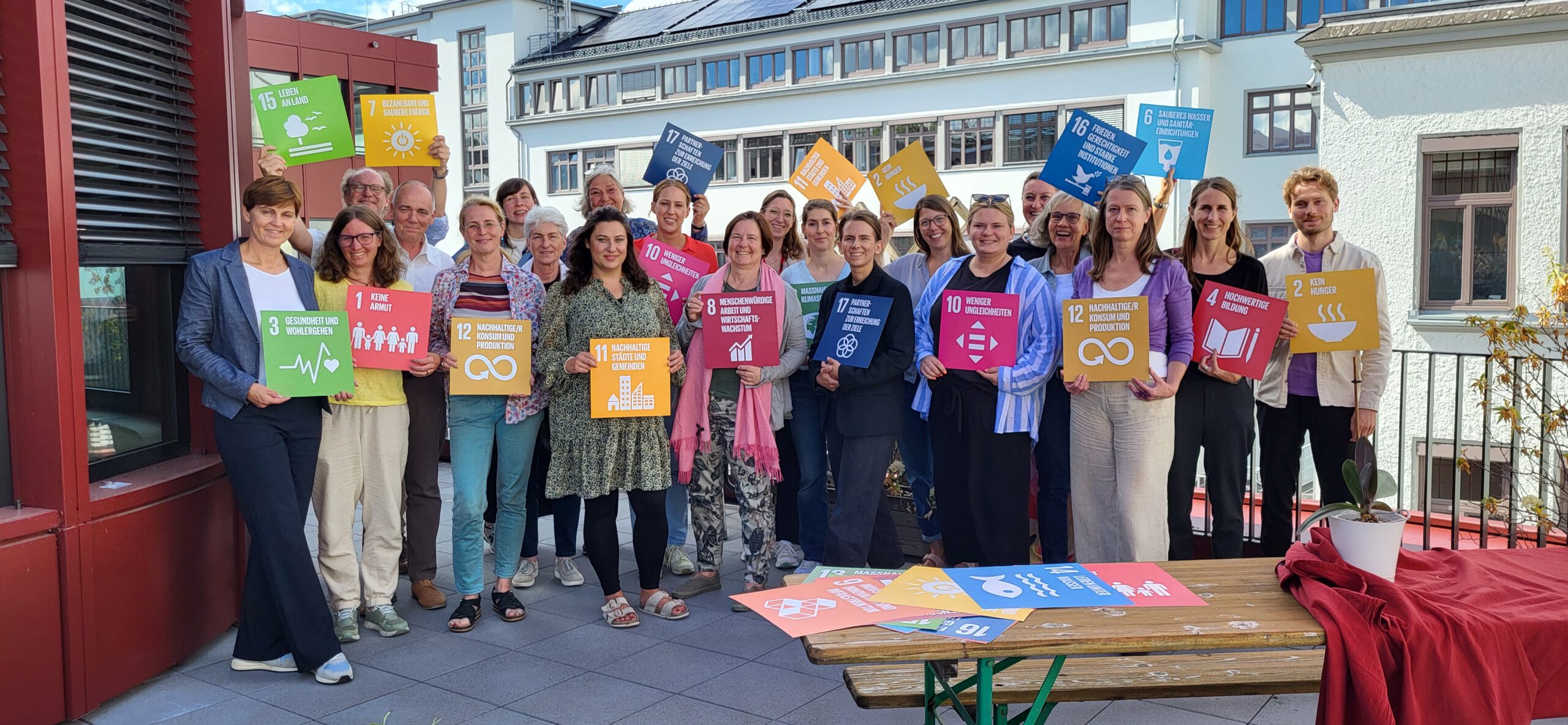 Mitglieder des Bündnisses für Nachhaltigkeit bei der Veranstaltung zum fünfjährigen Jubiläum. Bitte Schilder in den Händen zeigen Botschaften zu Nachaltigkeitsaspekten.
